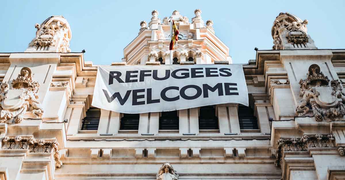 Sign on a historic building that says Refugees Welcome