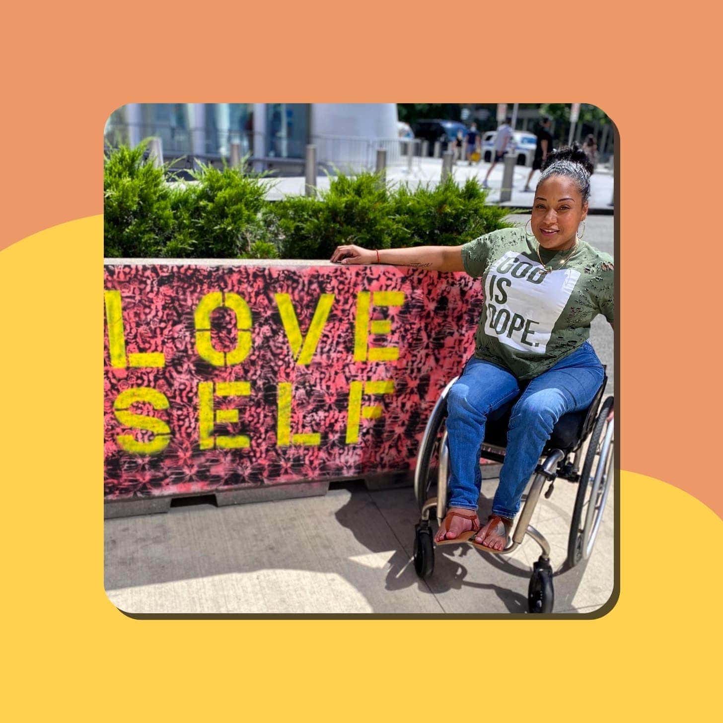 A Black woman wearing a shirt that says God Is Dope sits in a wheelchair next to a sign that says Love Self